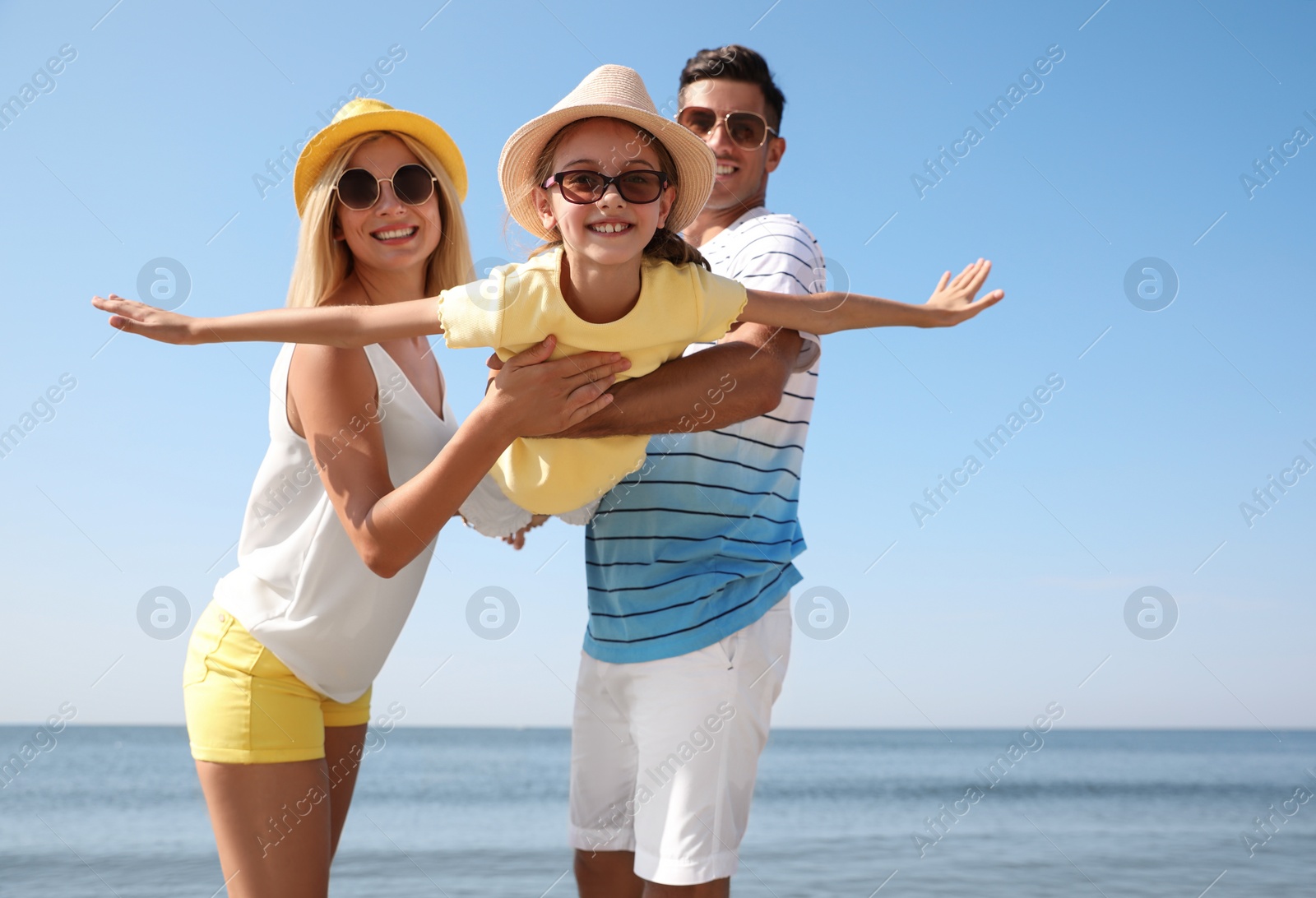 Photo of Parents playing with daughter at beach. Family vacation