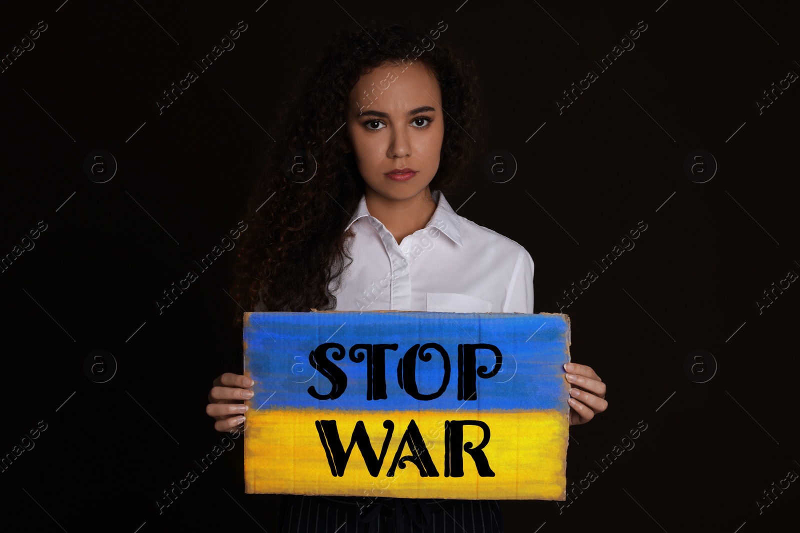 Image of Unhappy African American woman holding sign with phrase Stop War on black background