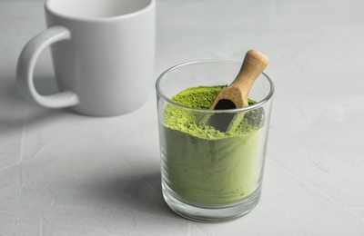 Photo of Glass with powdered matcha tea and scoop on table