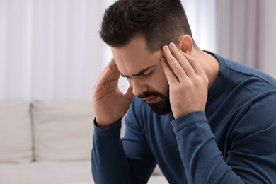 Man suffering from headache on sofa at home