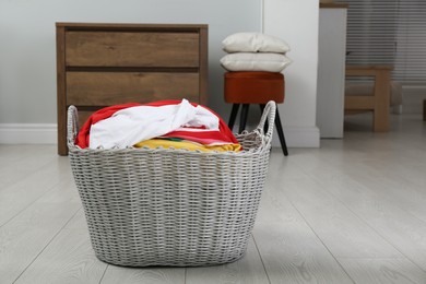 Photo of Wicker basket with dirty laundry on sofa indoors