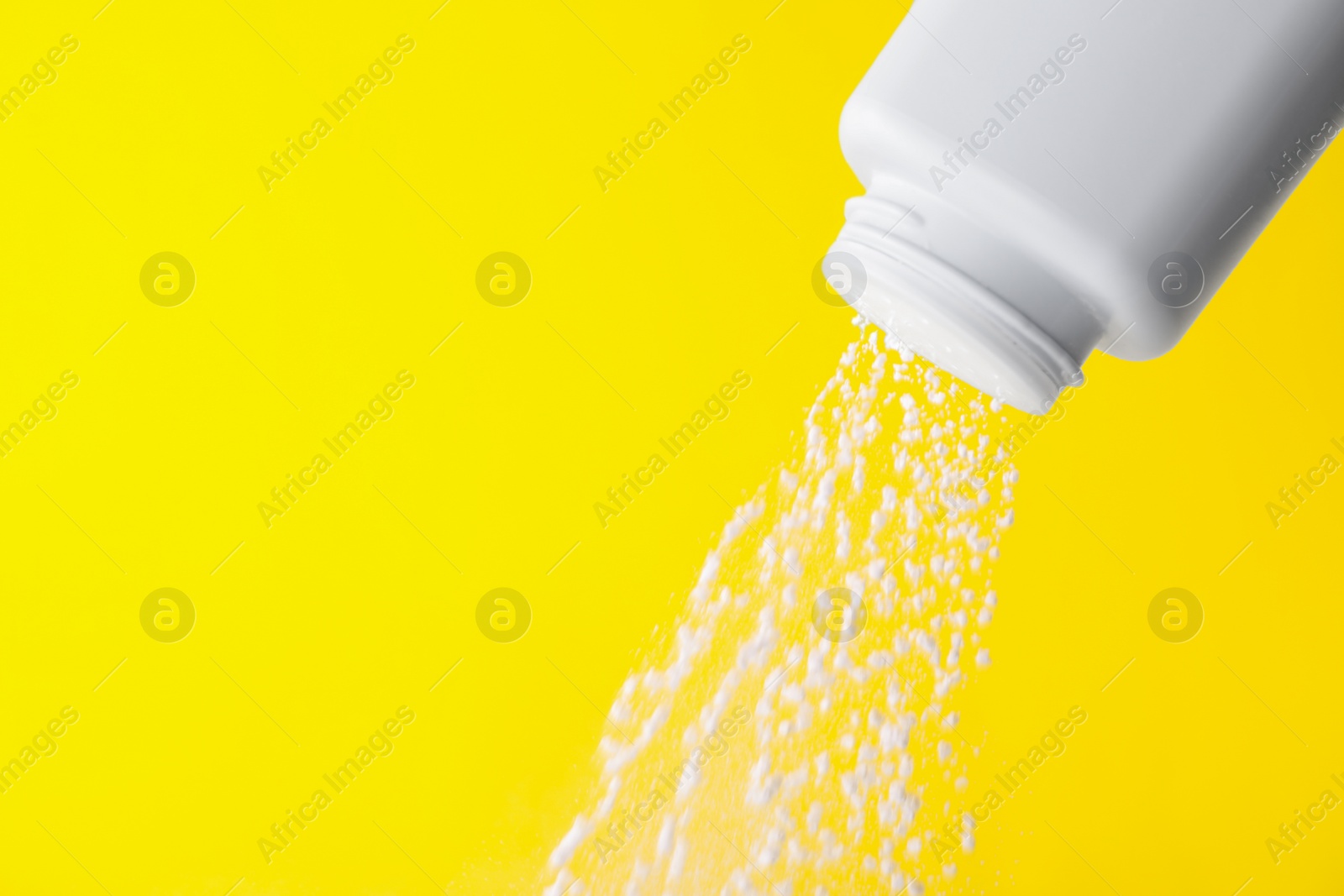 Photo of Scattering of baby powder on yellow background, closeup. Space for text