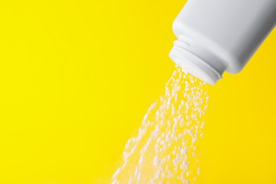 Scattering of baby powder on yellow background, closeup. Space for text