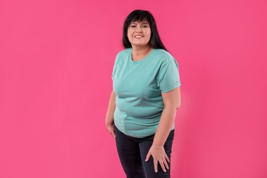 Beautiful overweight mature woman with charming smile on pink background