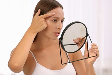Photo of Woman with skin problem looking at mirror indoors