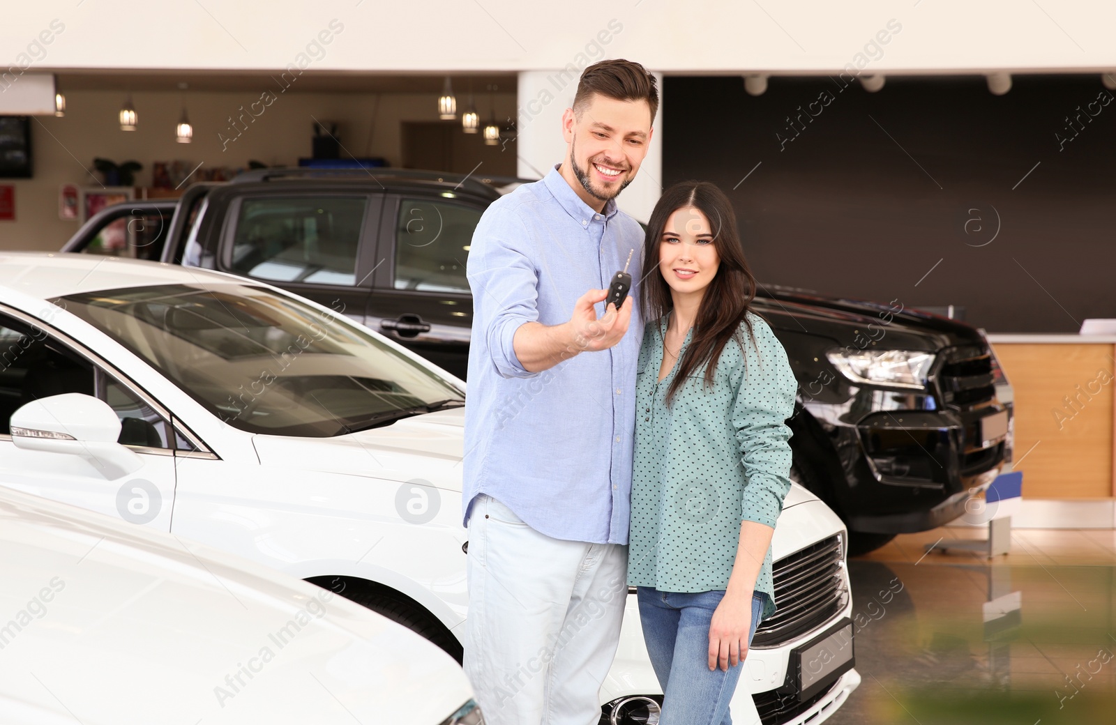 Photo of Young couple with key in salon. Buying new car