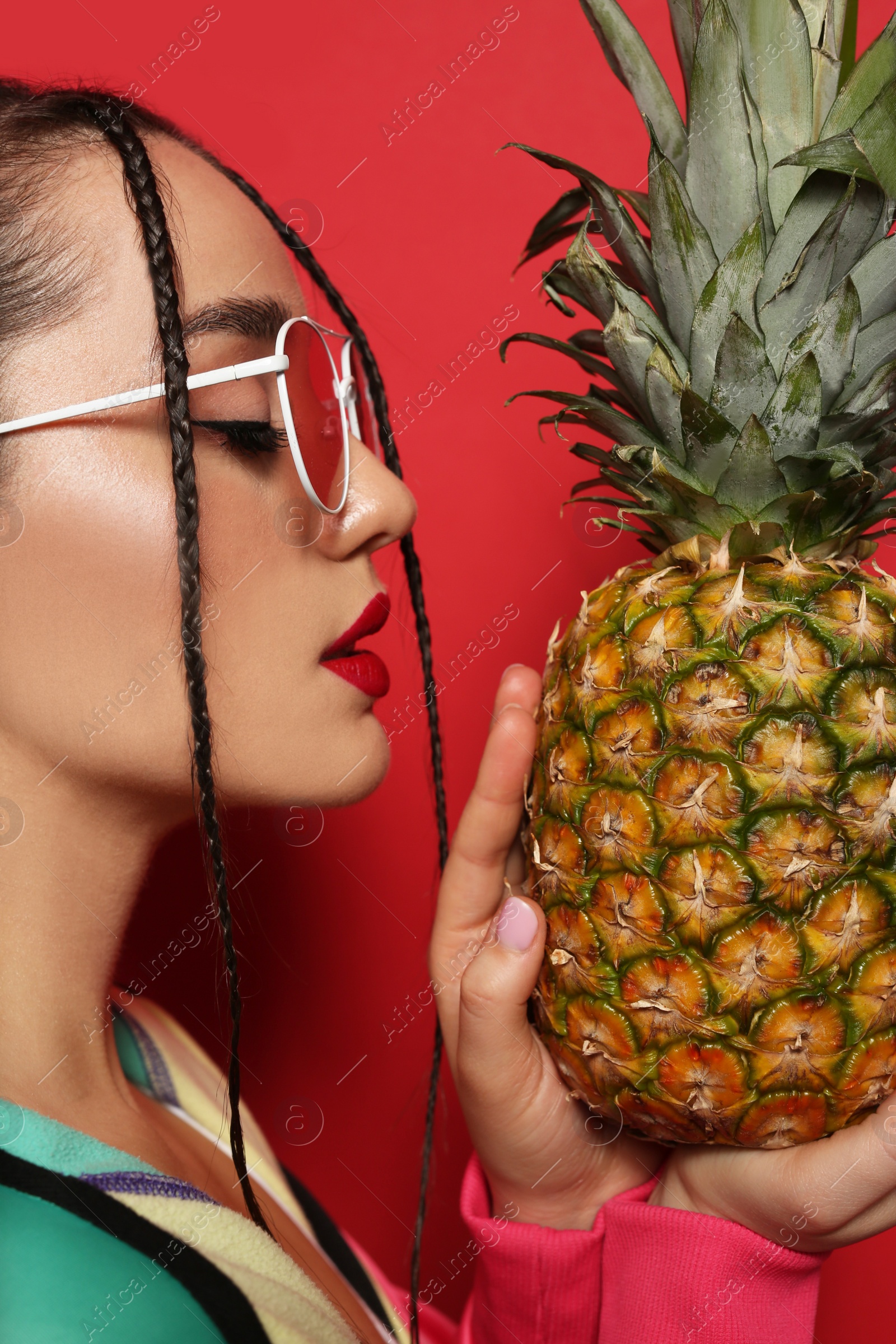 Photo of Young woman with fresh pineapple on red background. Exotic fruit