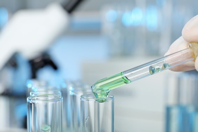 Analyst dripping reagent into test tube with sample at laboratory, closeup. Chemical analysis