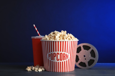 Photo of Composition with popcorn and cinema reel on table against color background