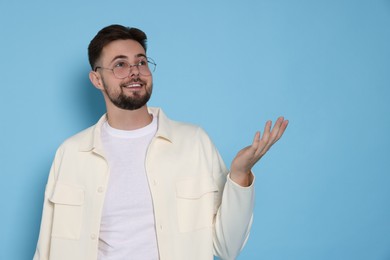 Handsome man in white jacket on light blue background, space for text