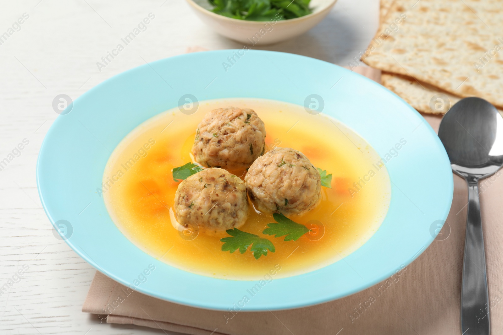 Photo of Dish of Jewish matzoh balls soup on white wooden table