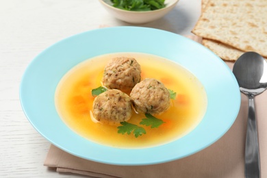 Dish of Jewish matzoh balls soup on white wooden table