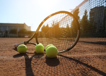 Tennis balls and racket on clay court