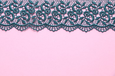 Photo of Green lace on pink background, top view. Space for text