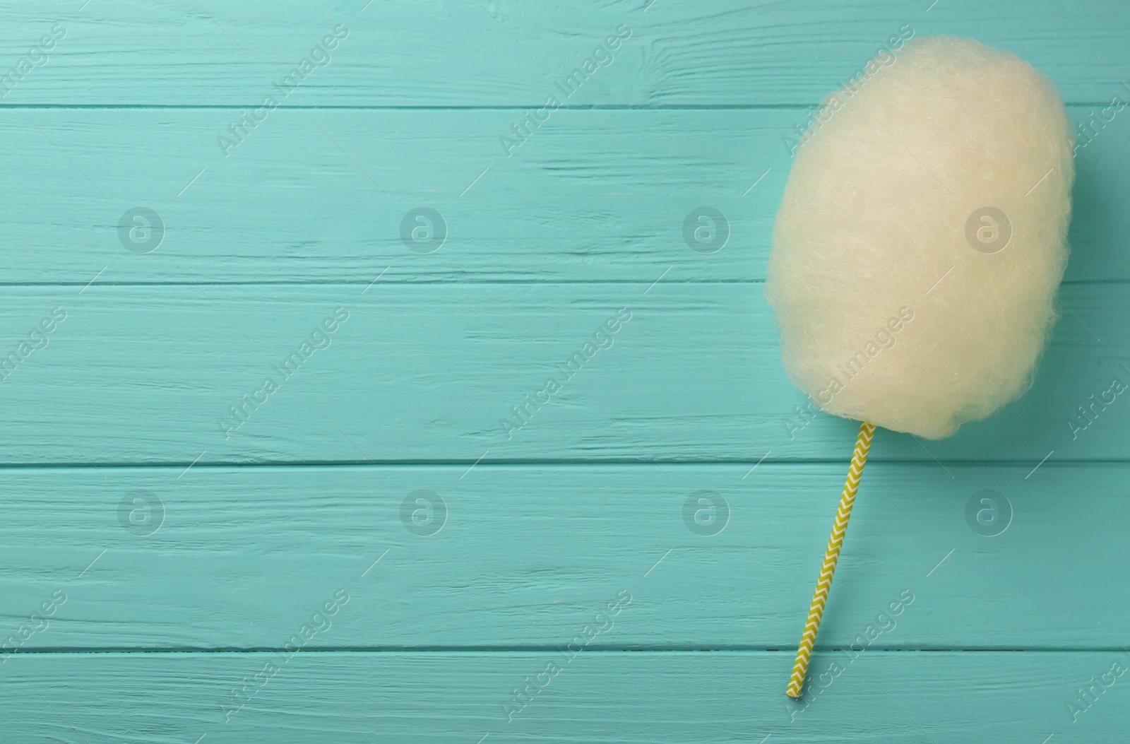 Photo of One sweet cotton candy on turquoise wooden table, top view. Space for text