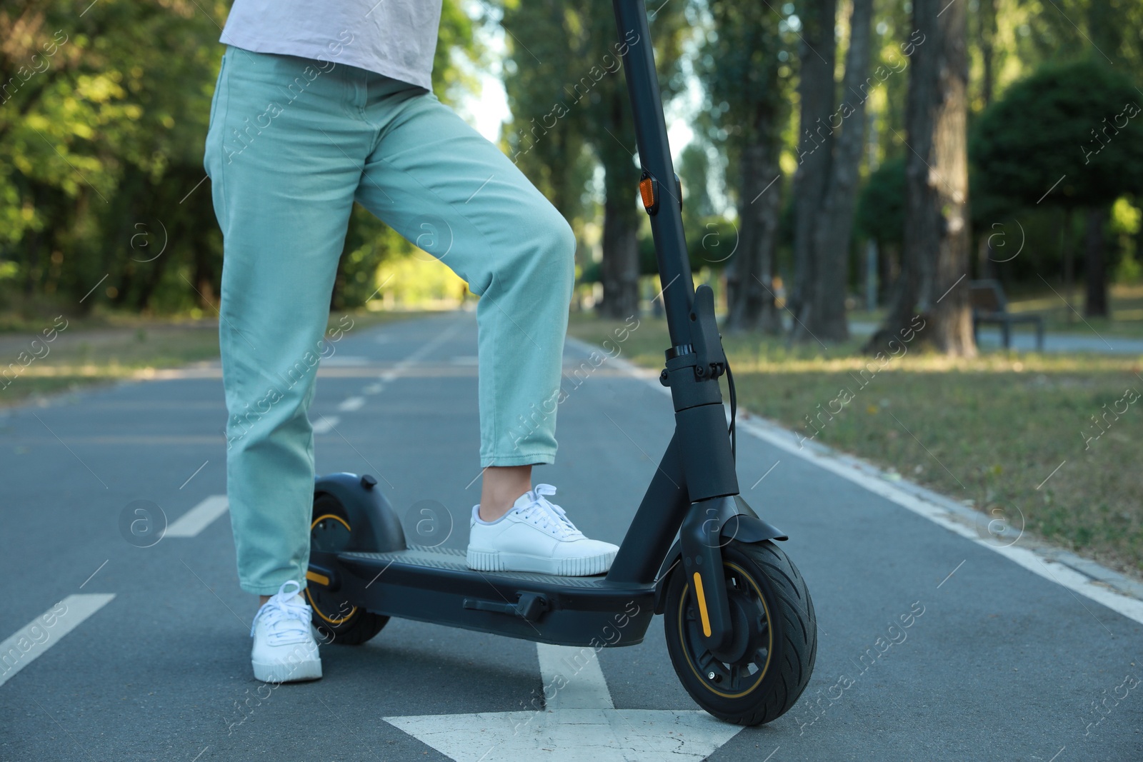 Photo of Woman with modern electric kick scooter in park, closeup