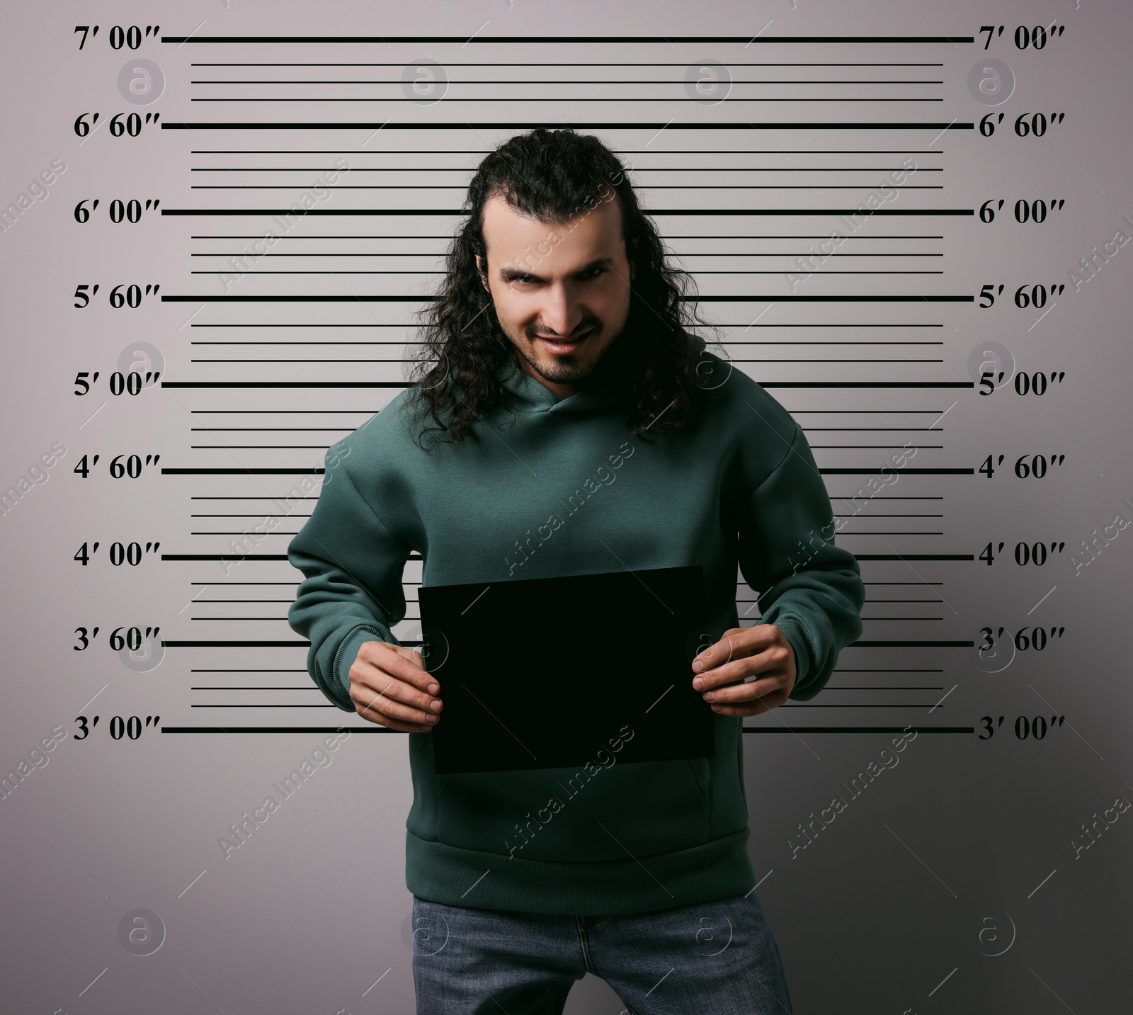 Image of Criminal mugshot. Arrested man with blank card against height chart