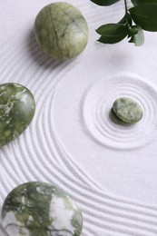 Photo of Zen concept. Stones, leaves and pattern on white sand, above view