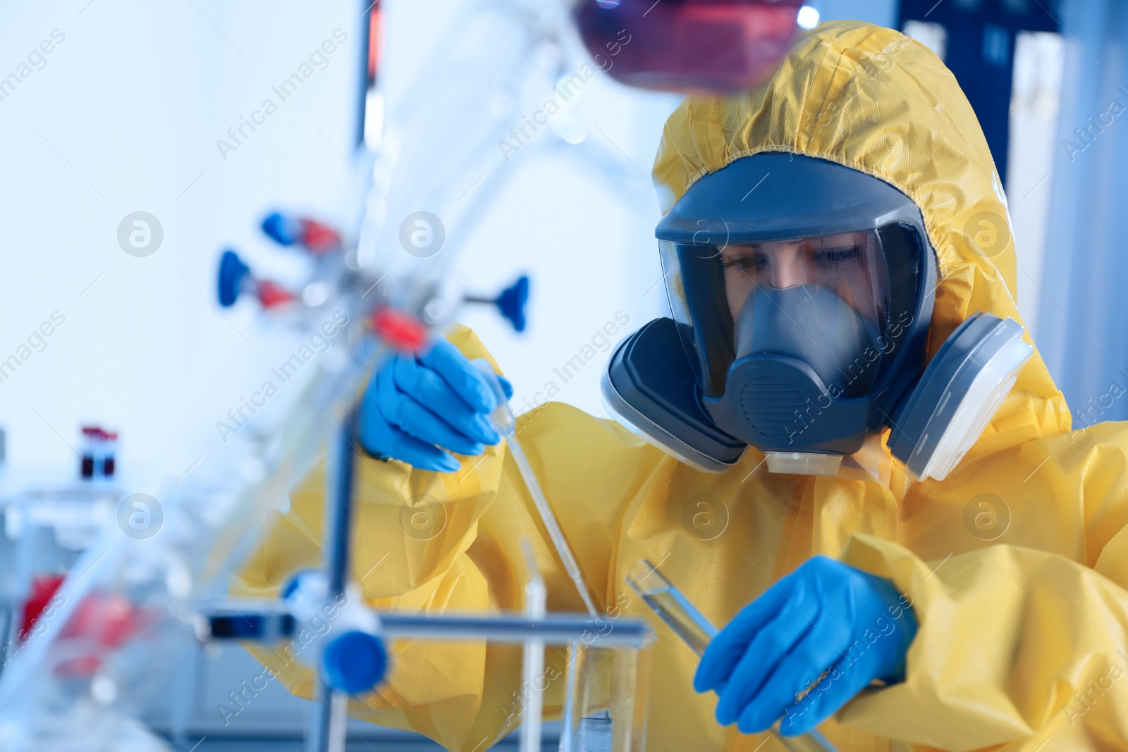 Photo of Scientist in chemical protective suit dripping reagent  into test tube at laboratory. Virus research