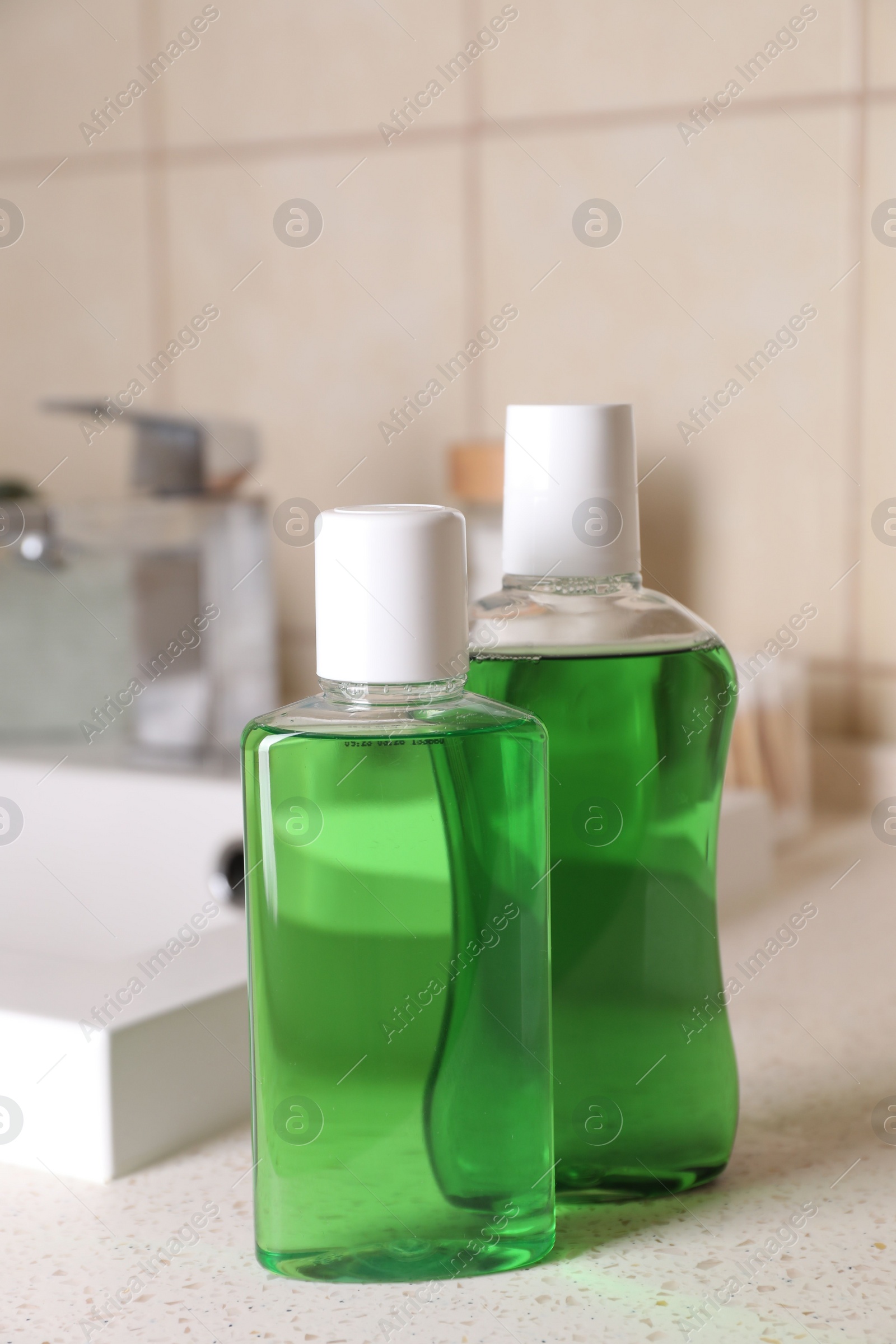 Photo of Fresh mouthwashes in bottles on countertop in bathroom, closeup