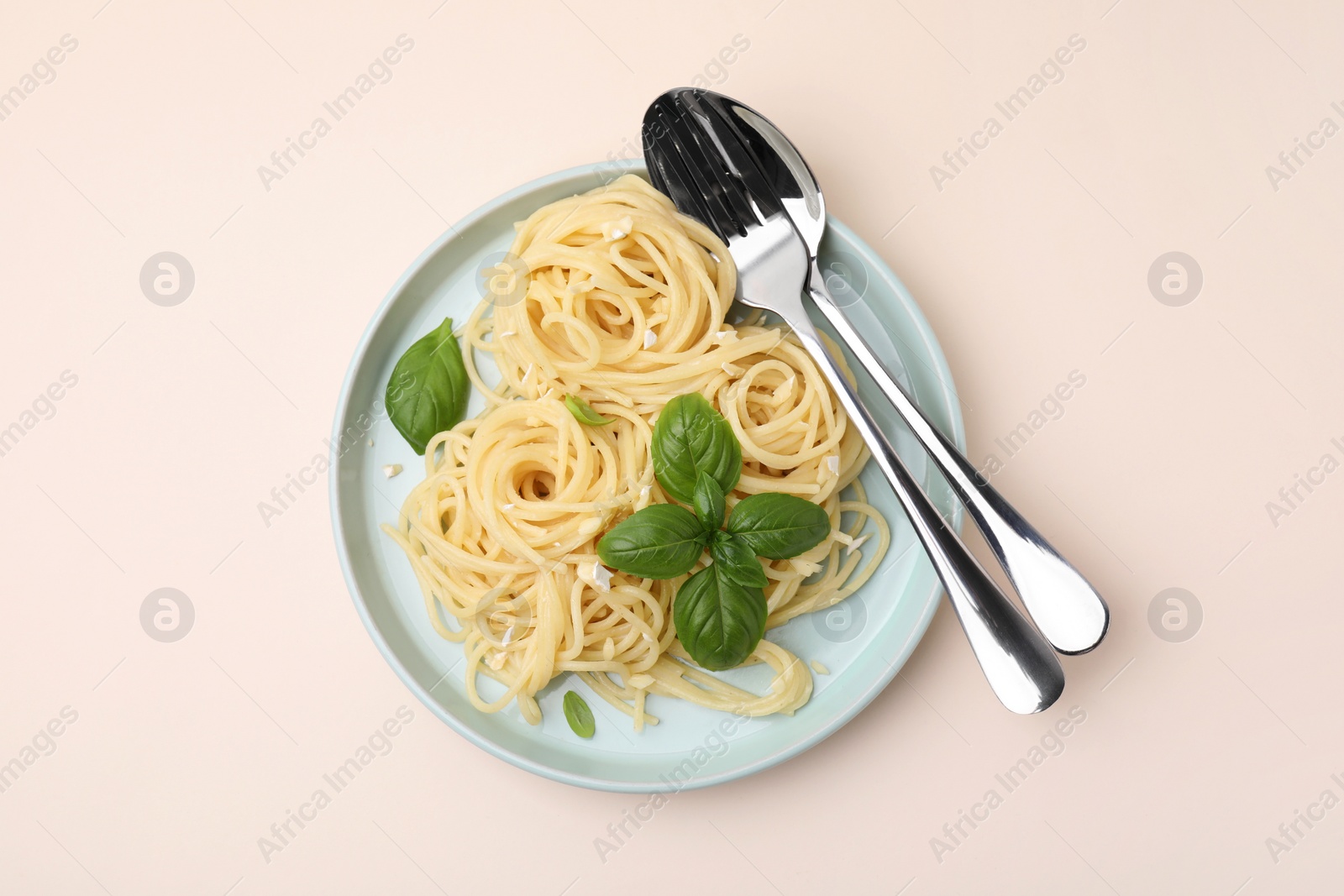 Photo of Delicious pasta with brie cheese and basil leaves on beige table, top view