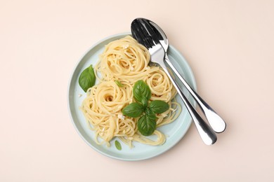 Photo of Delicious pasta with brie cheese and basil leaves on beige table, top view