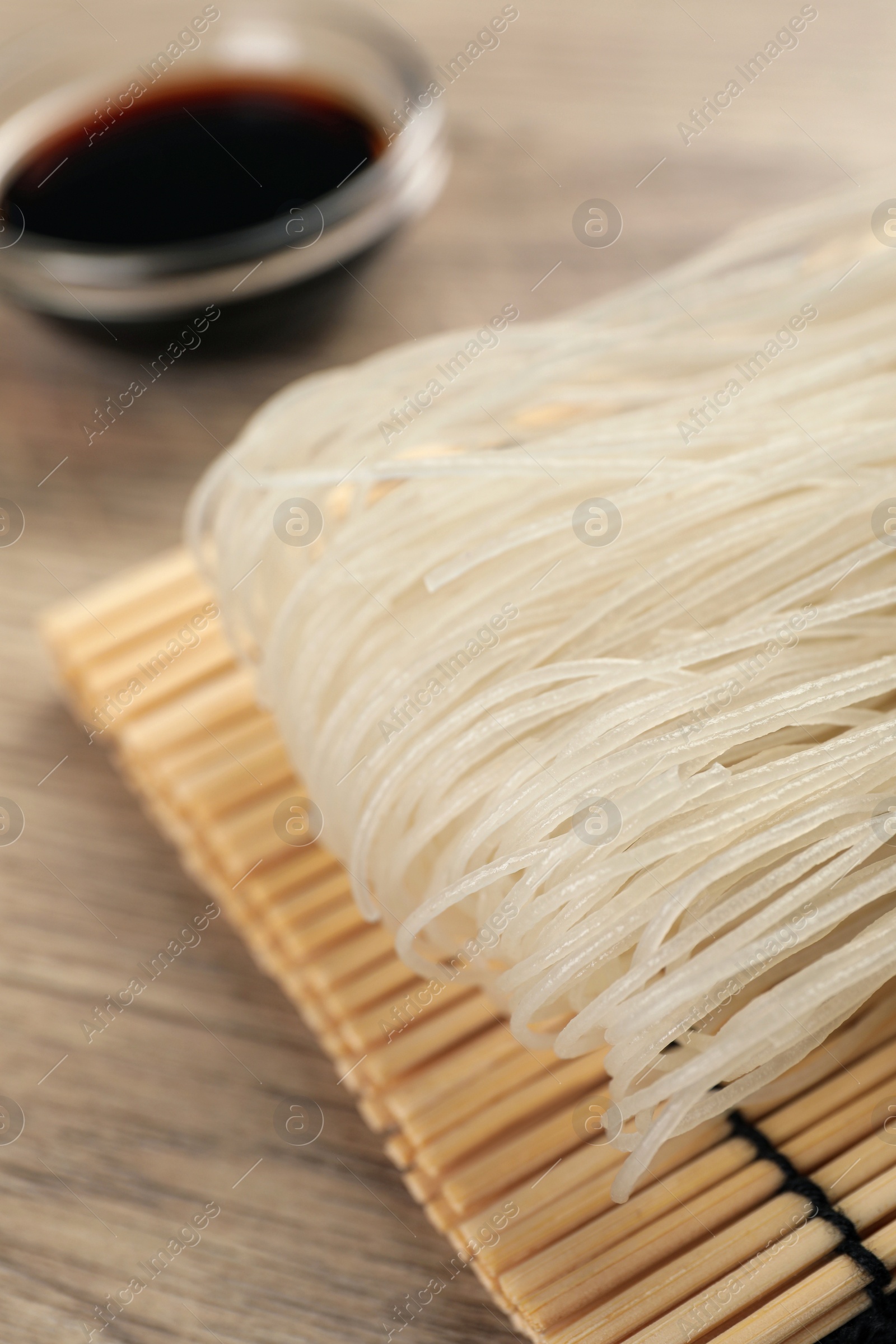 Photo of Dried rice noodles with soy sauce on wooden table, closeup