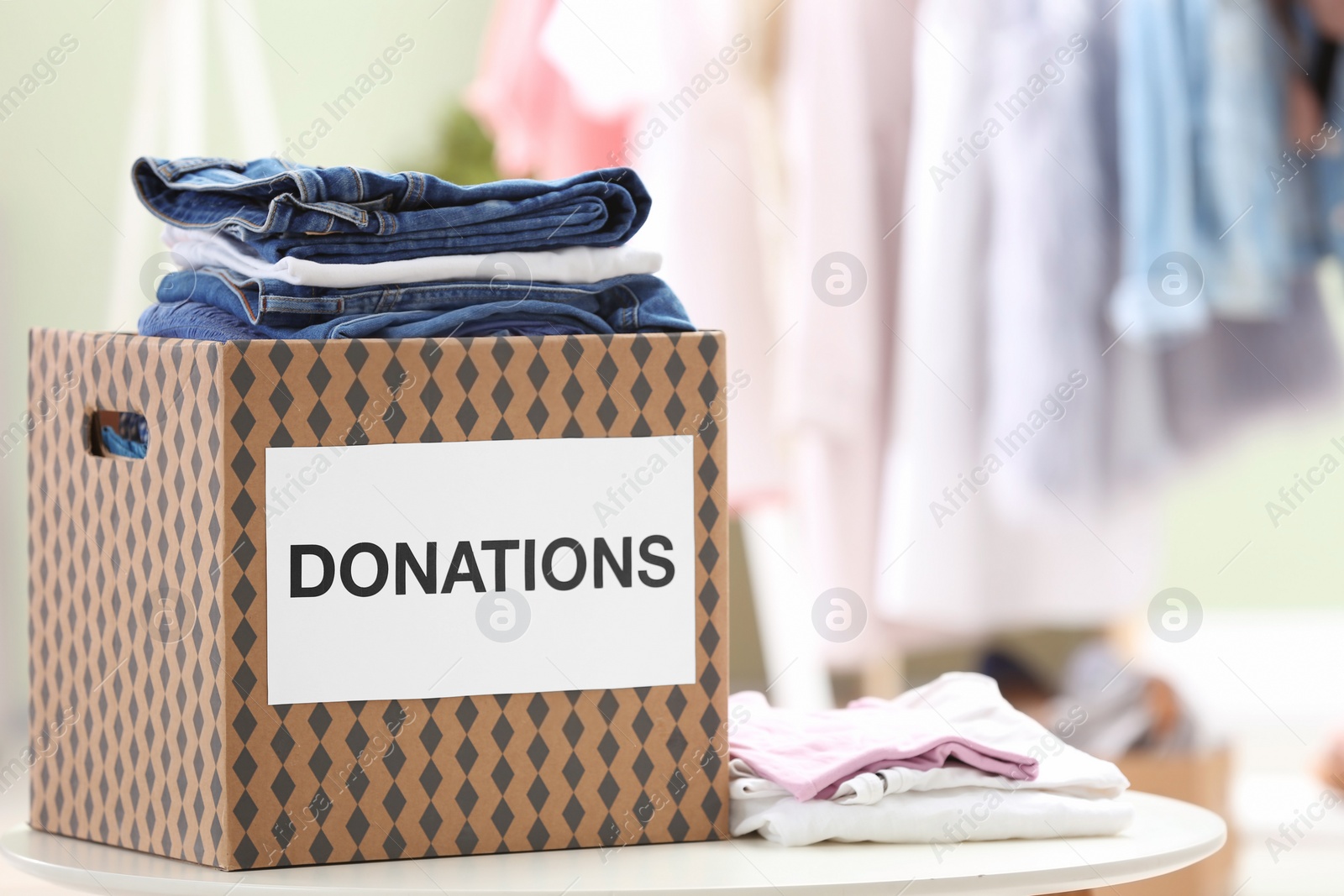 Photo of Donation box with clothes on table indoors