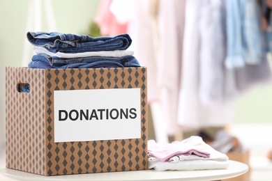 Donation box with clothes on table indoors