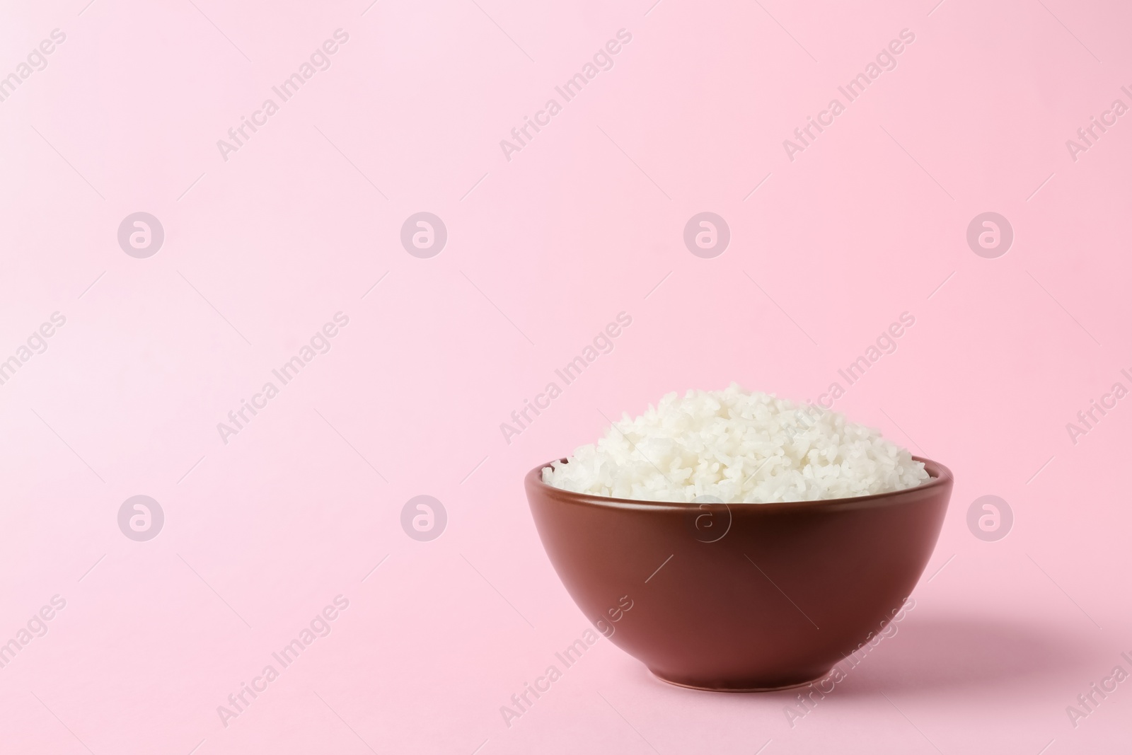 Photo of Bowl of boiled rice on color background. Space for text