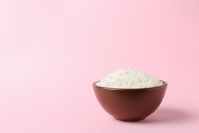 Photo of Bowl of boiled rice on color background. Space for text