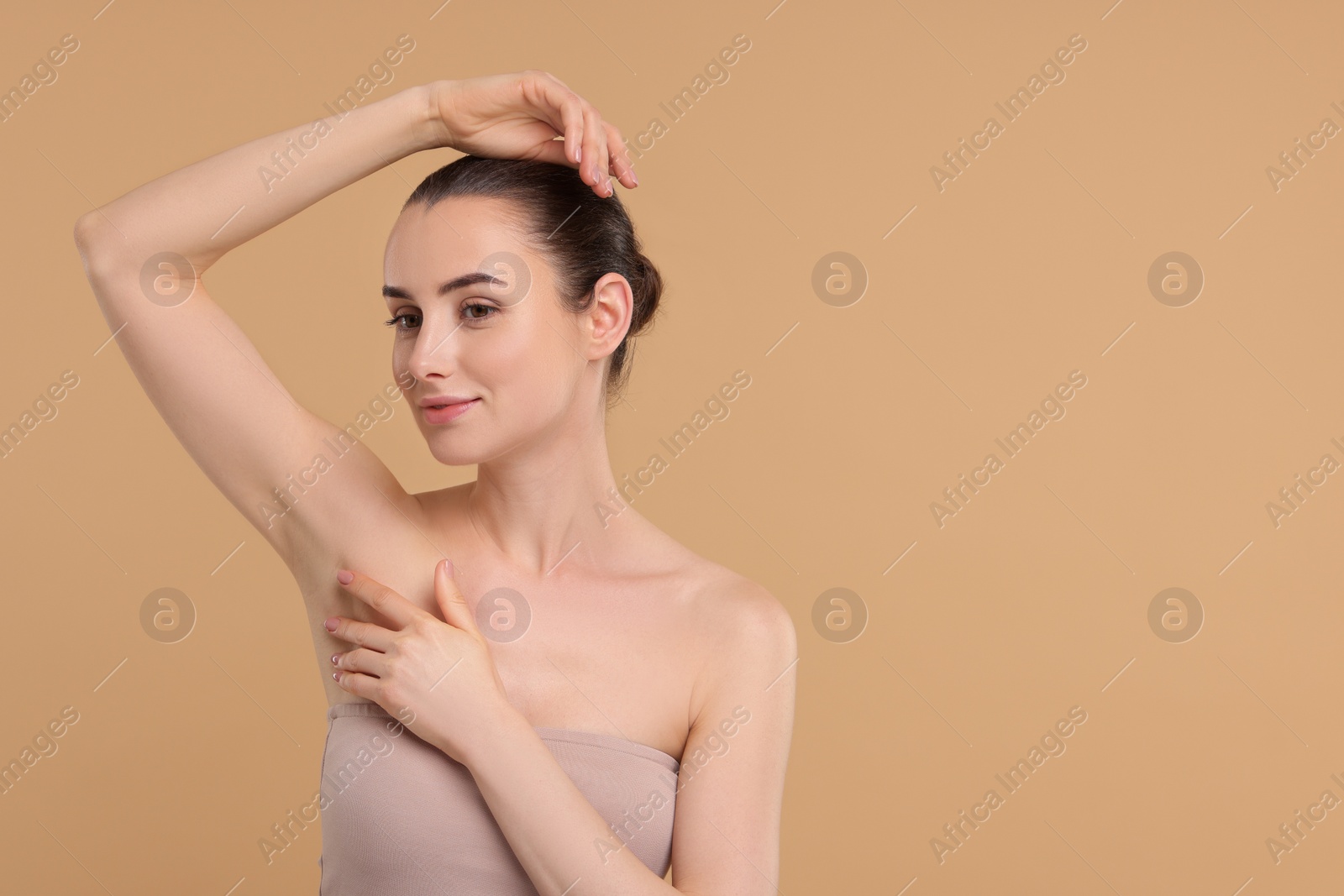 Photo of Beautiful woman showing armpit with smooth clean skin on beige background, space for text