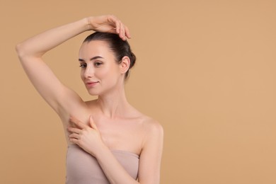 Photo of Beautiful woman showing armpit with smooth clean skin on beige background, space for text
