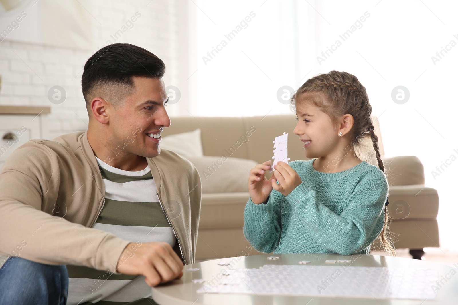 Photo of Happy father and his daughter playing with puzzles at home