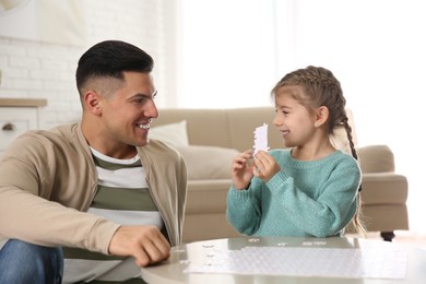 Happy father and his daughter playing with puzzles at home