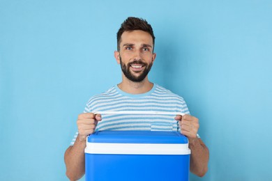 Photo of Happy man with cool box on light blue background