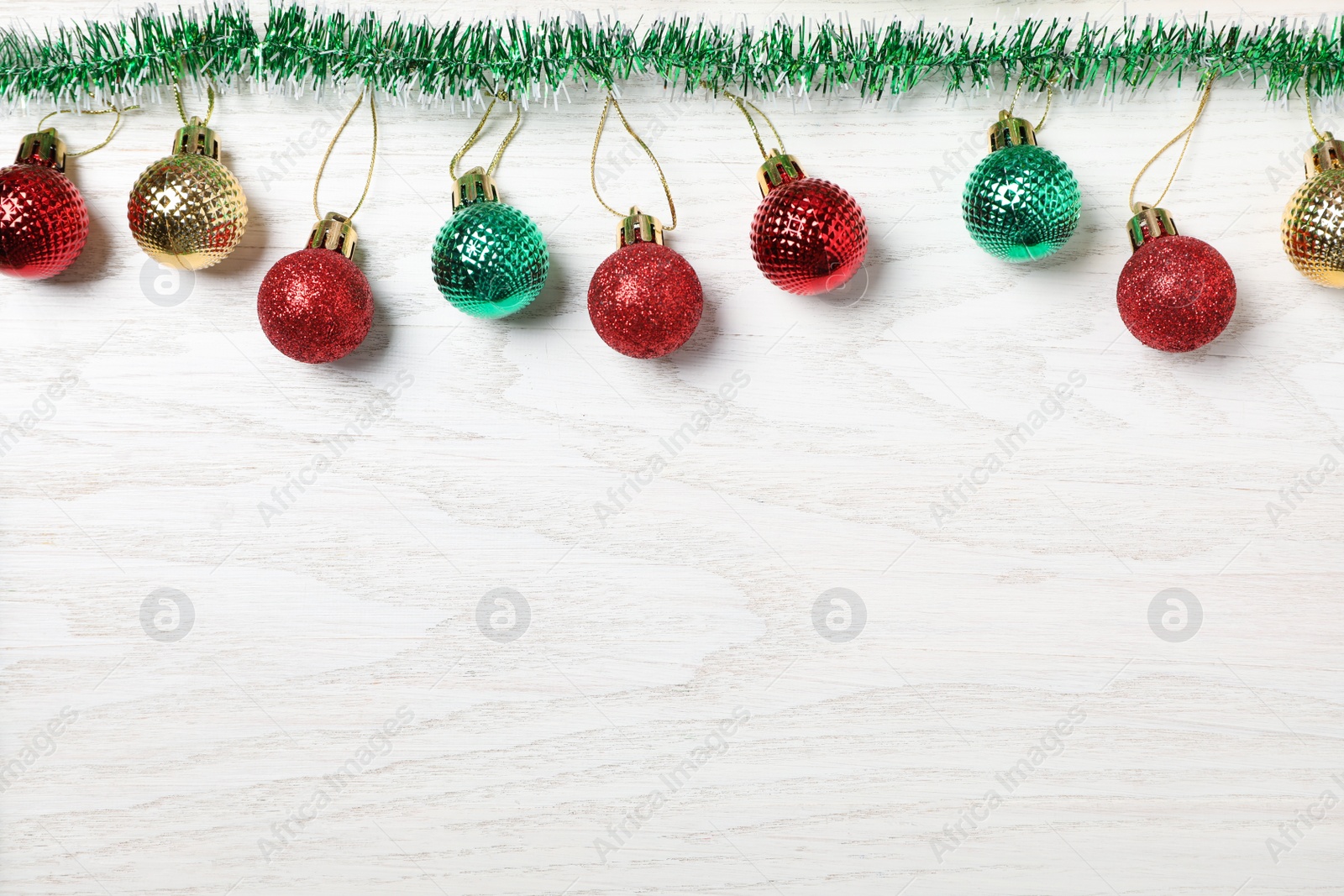 Photo of Bright tinsel and Christmas balls on white wooden background, flat lay. Space for text