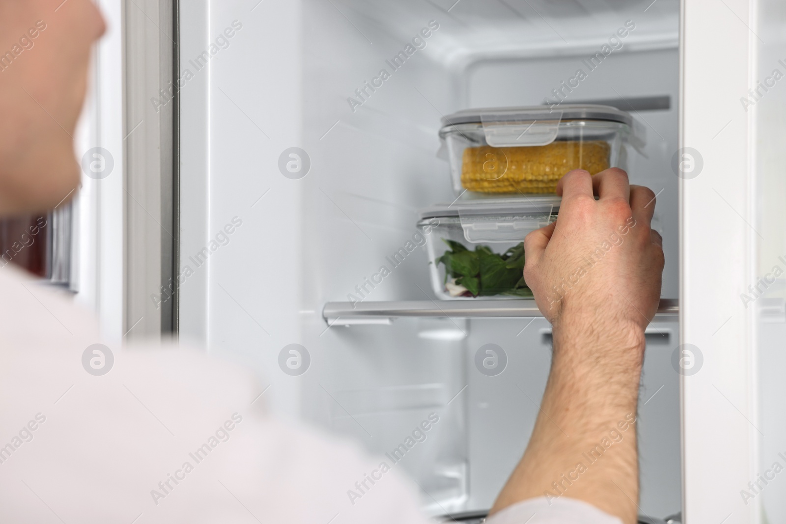 Photo of Man taking containers with vegetables out of refrigerator, closeup