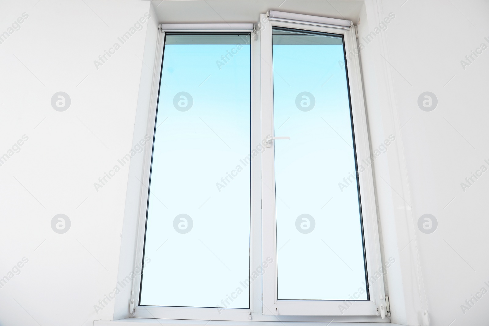 Photo of View of blue sky through modern window in light wall indoors