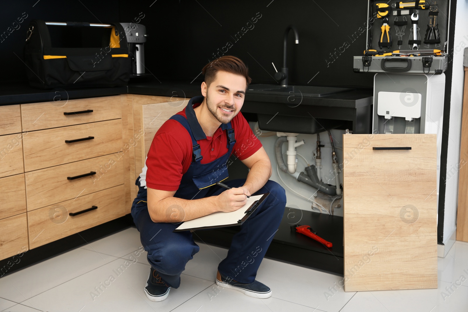 Photo of Male plumber with clipboard near kitchen sink. Repair service