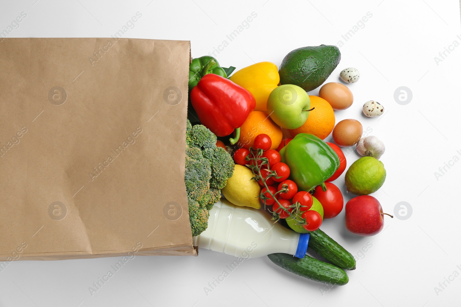 Photo of Paper bag with different groceries on white background, top view