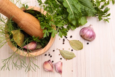 Photo of Mortar with pestle and different ingredients on wooden table, flat lay