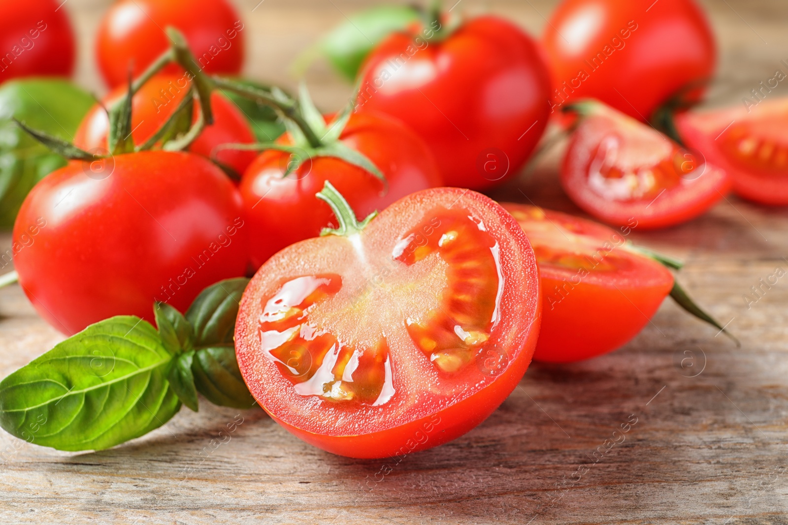 Photo of Fresh cherry tomatoes with basil on wooden background, closeup