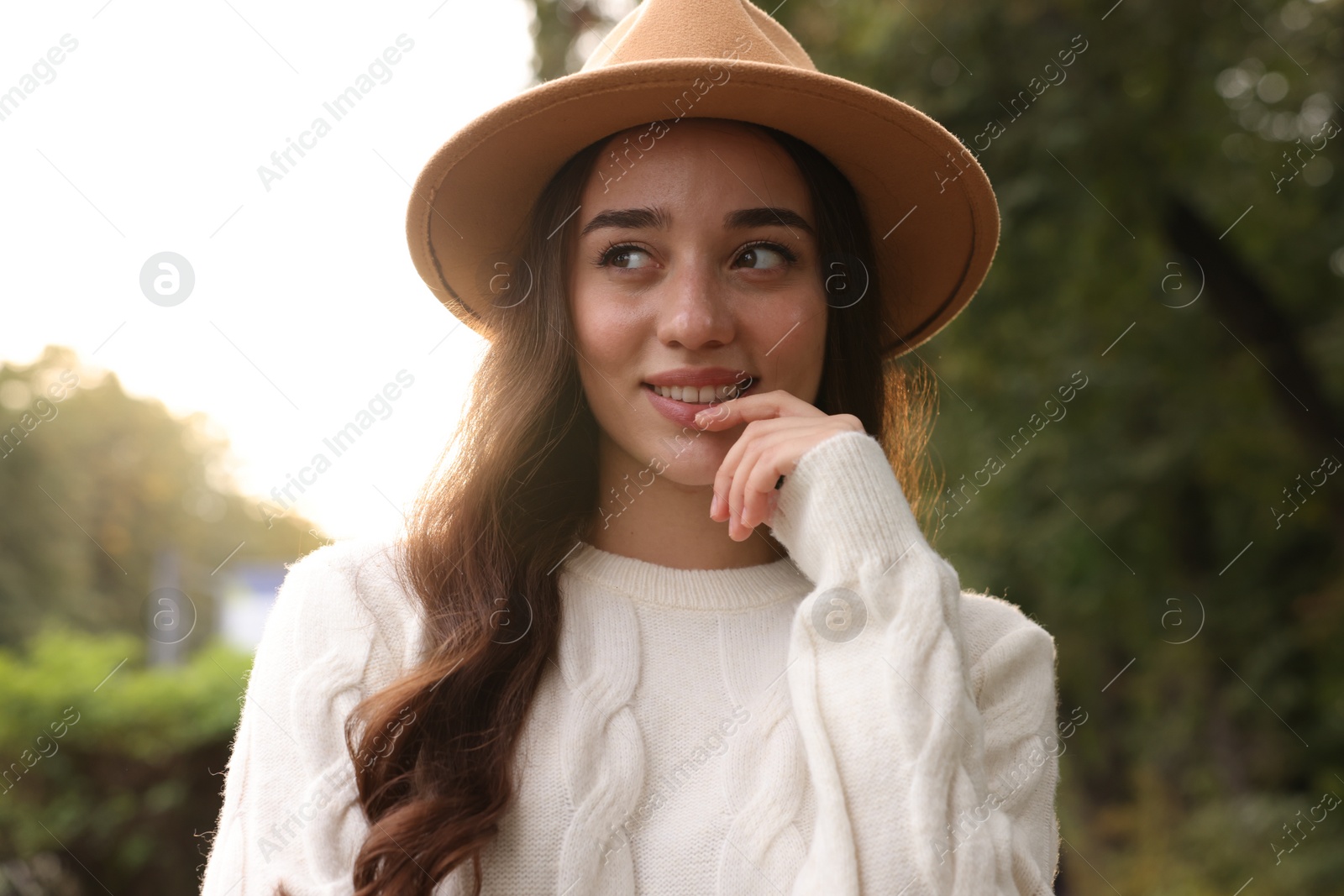 Photo of Beautiful young woman in stylish warm sweater and hat outdoors