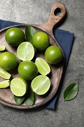 Photo of Fresh ripe limes and leaves on grey table, top view