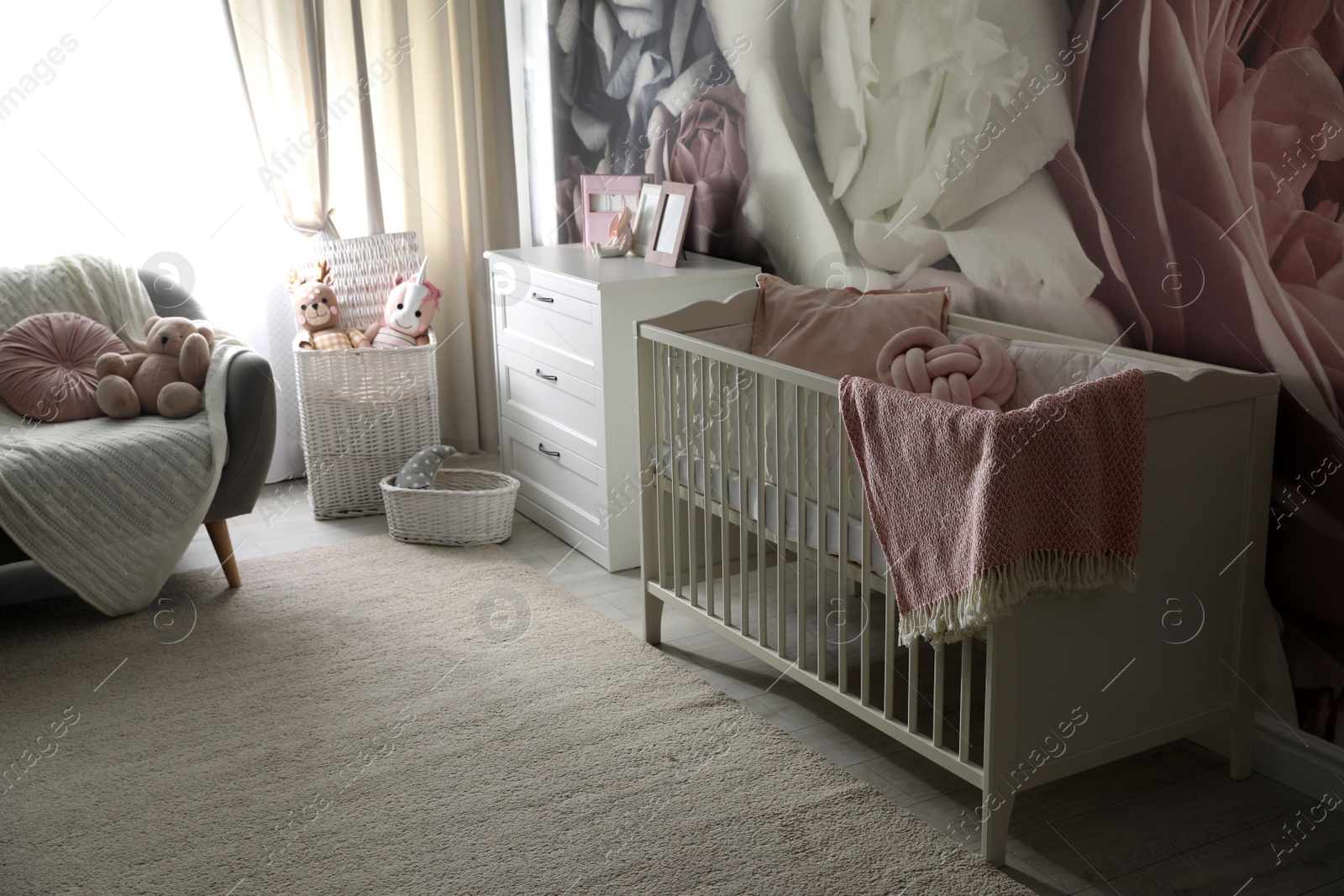 Photo of Baby room interior with stylish crib and floral wallpaper