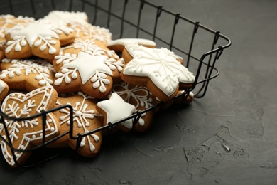 Photo of Tasty Christmas cookies with icing on black table, closeup. Space for text