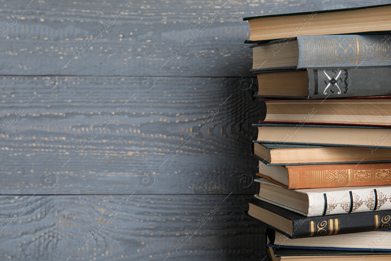 Photo of Stack of hardcover books on grey wooden background. Space for text