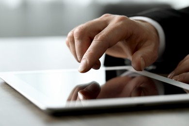 Closeup view of man using new tablet at desk indoors