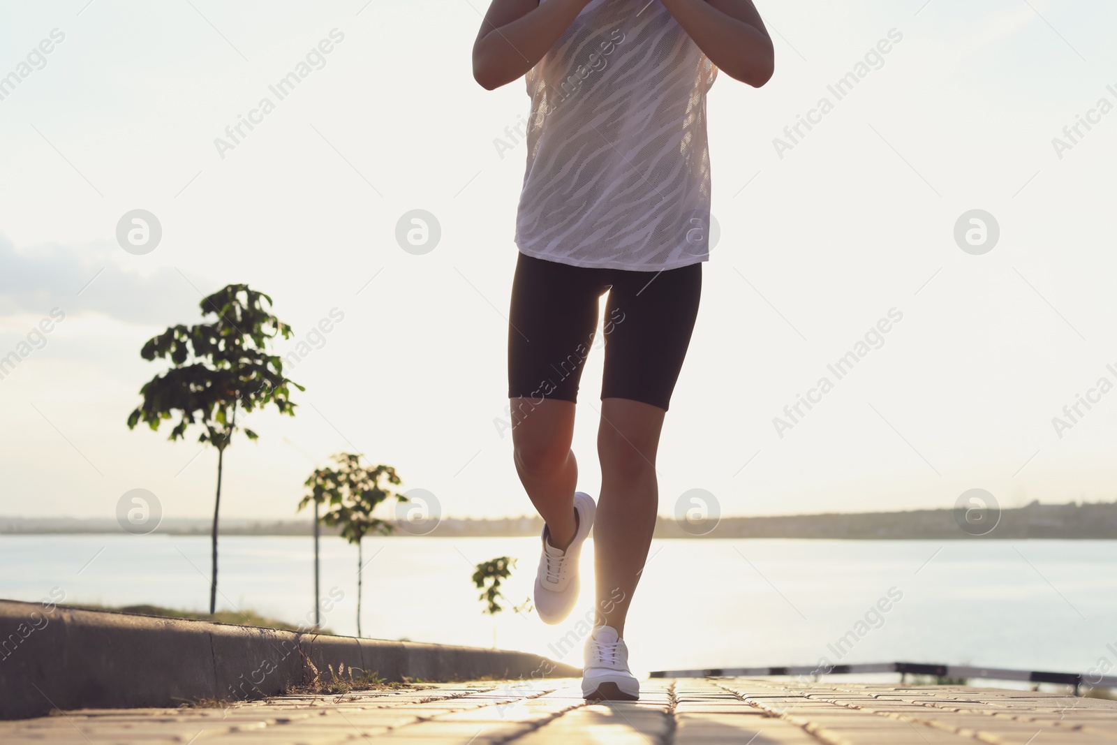 Photo of Young woman running near river in morning, closeup